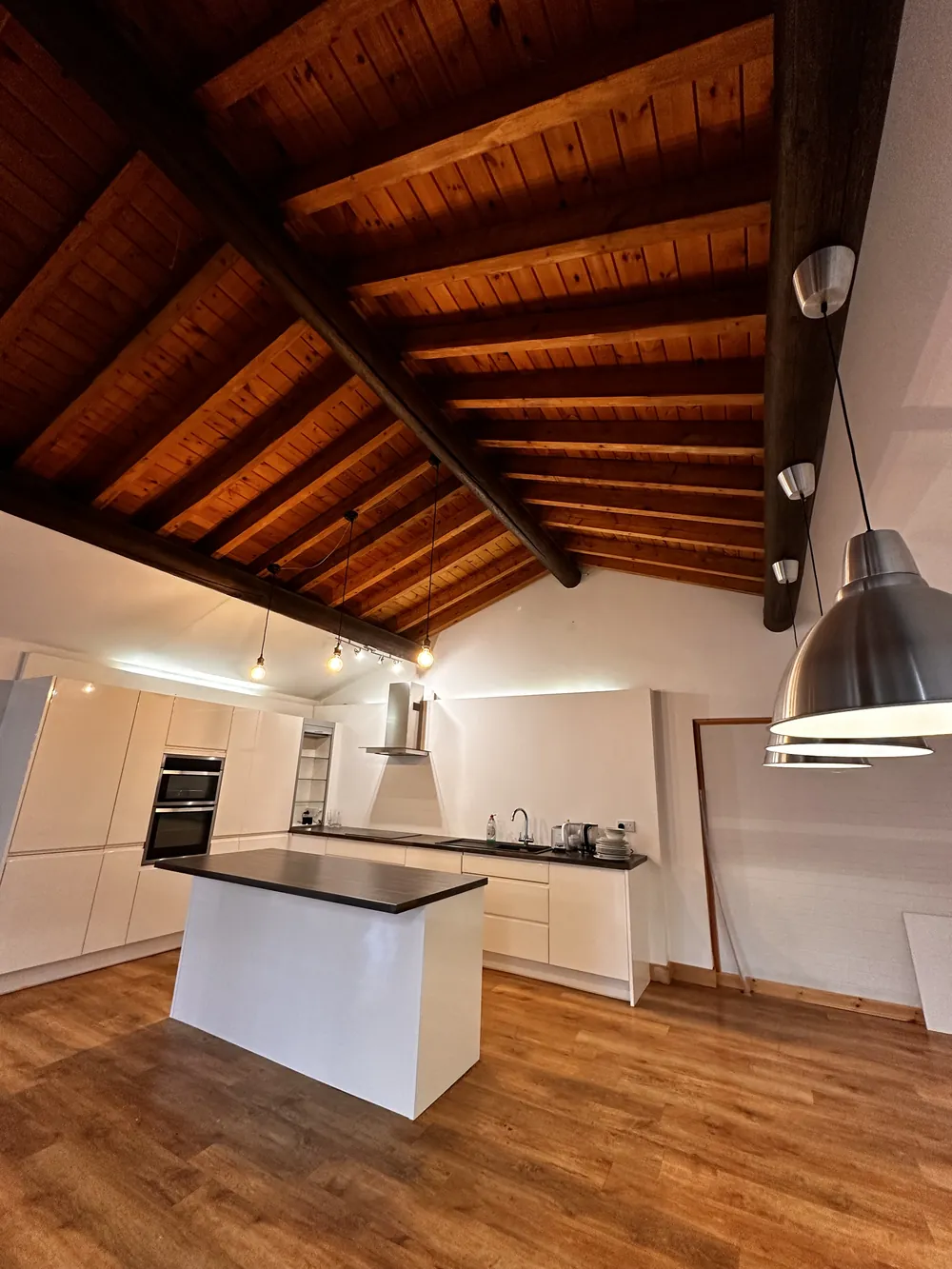 Fitted kitchen with island beneath a timber-beamed ceiling