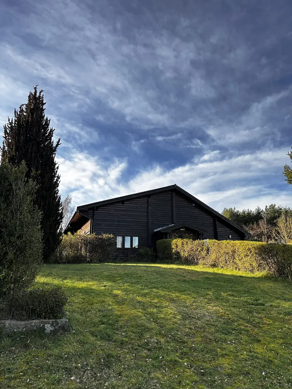 The Log Cabin seen across the lawn under a big sky