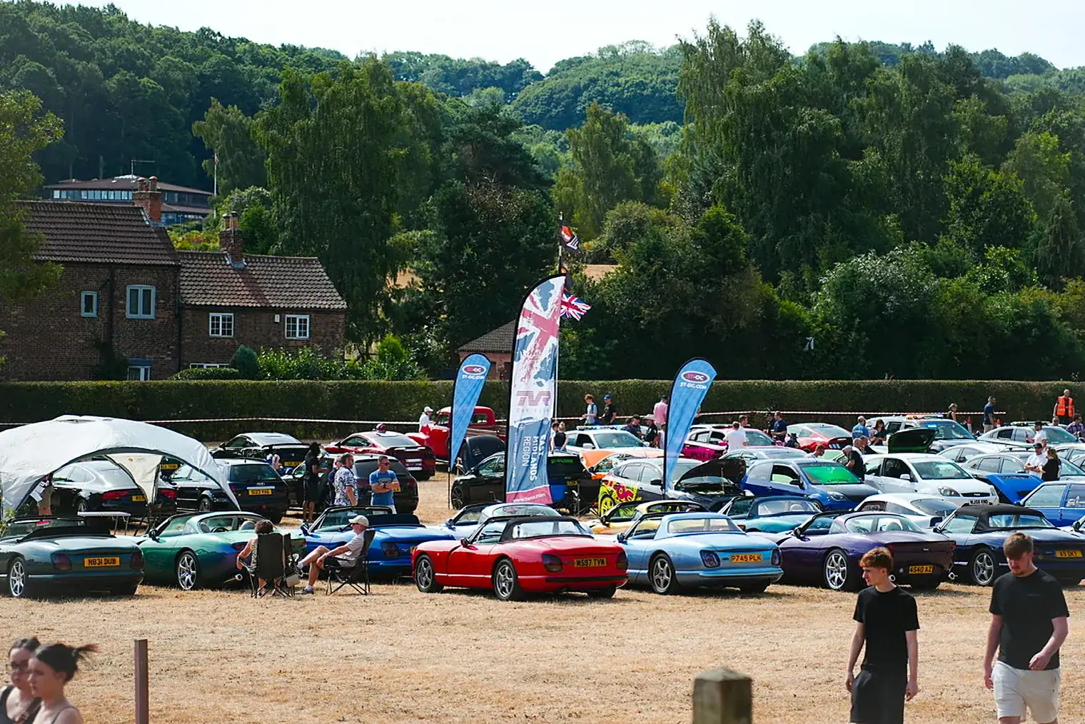 Classic cars beneath flags on the show field