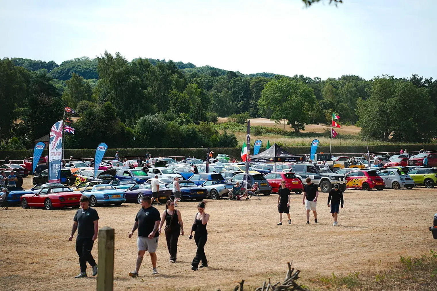 Visitors walking among rows of cars on the festival fields