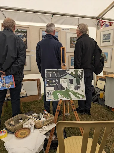 Visitors browsing paintings inside an art marquee